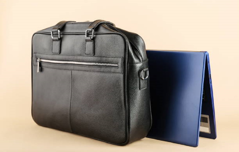 men's leather bag and laptop are on a light brown background